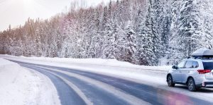 Suv car with rooftop cargo carrier trunk stay on roadside of winter road. Family trip to ski resort. Winter holidays adventure. car on winter road