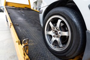 Closeup on car towed onto flatbed tow truck with cable being donated for carity