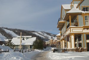 "The sun is just rising over the village of Blue Mountain Ski Resort in Collingwood, Ontario with a view up the main street with the ski runs in the background."