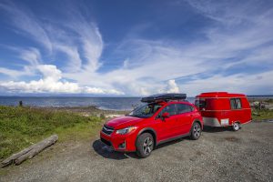 Red car and retro trailer, Vancouver Island, BC, Canada - May 10, 2018: Car camping with antique tiny trailer.