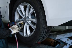 Mechanic uses drill to remove bolts from a vehicle on a lift