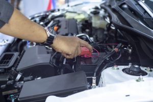 Hands of car mechanic working in battery check.