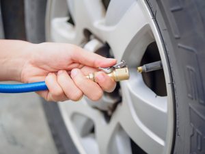 driver checking air pressure and filling air in the tires close up