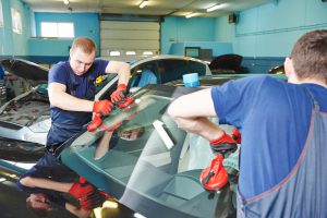 Two men installing a windshield