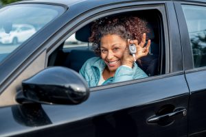 Black woman holding keys to new car and smiling at camera