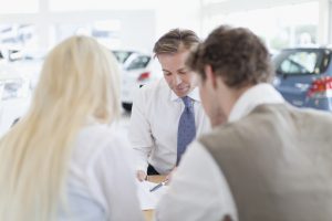 Car salesman with customers at desk