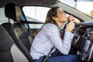 Young Woman Embracing Her New Car. Excited young woman and her new car indoors. Young and cheerful woman enjoying new car hugging steering wheel sitting inside