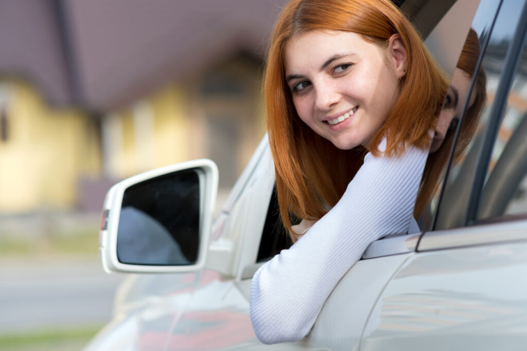 Young woman with red hair driving a car.