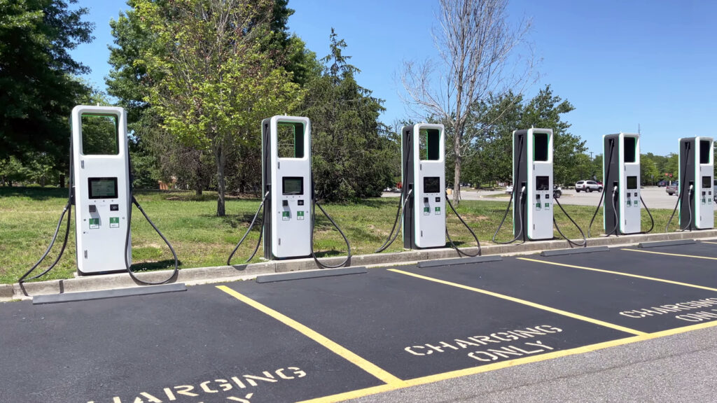 electric charging station with many electric chargers and a parking lot on a sunny day.