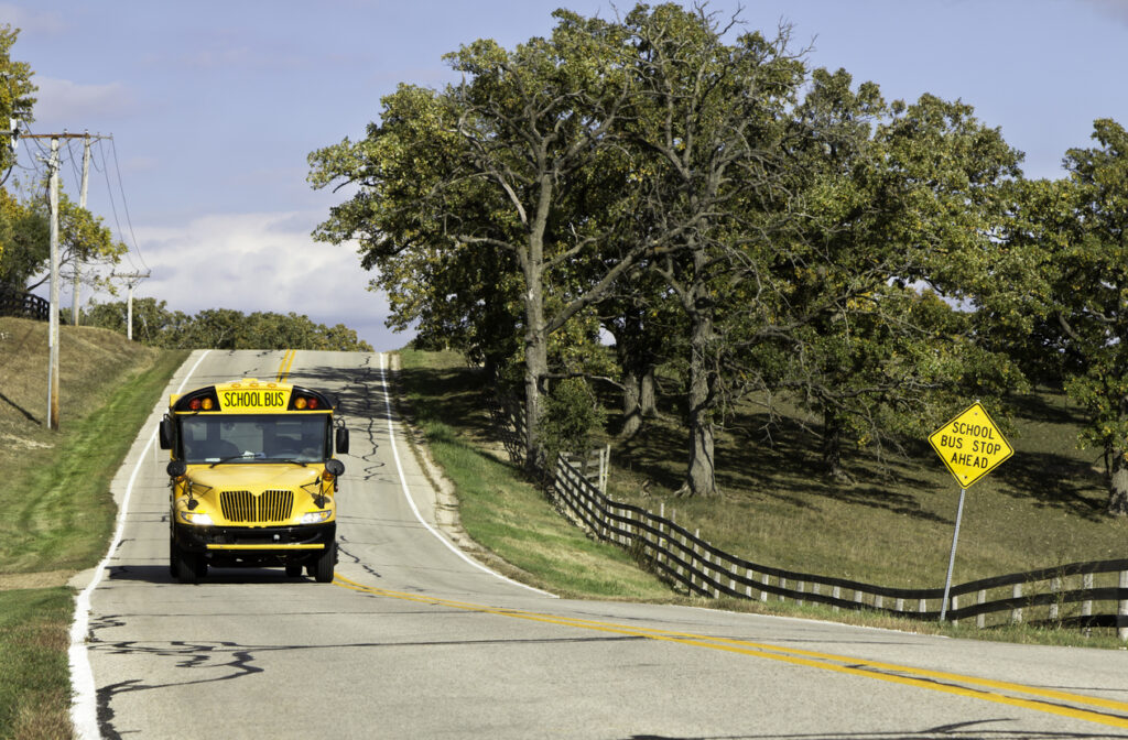 Country asphalt road with school bus coming.