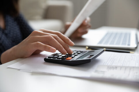 Close up young mixed race woman calculating expenses.